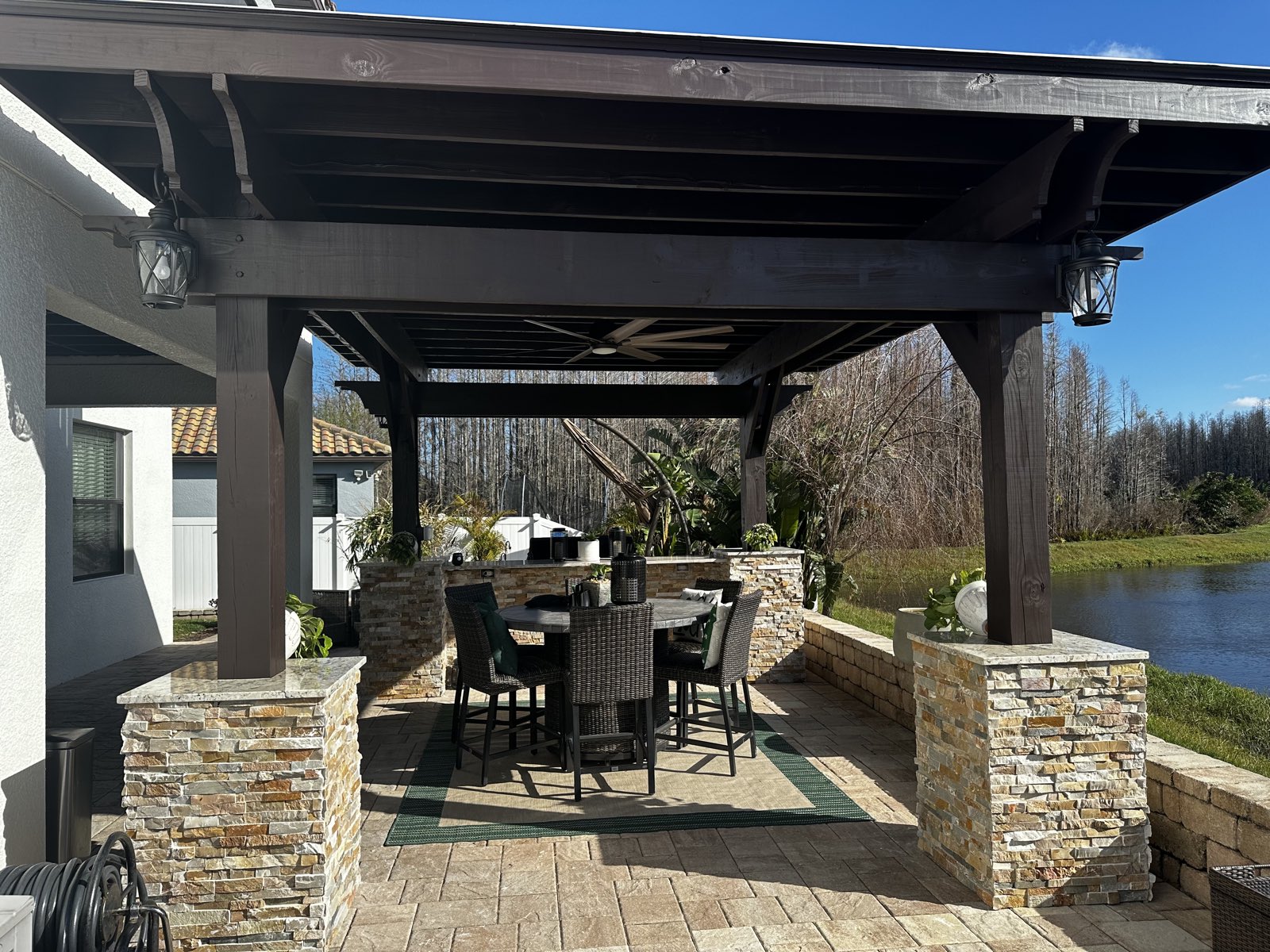 Timber pergola with stone columns overlooking a lake at sunset