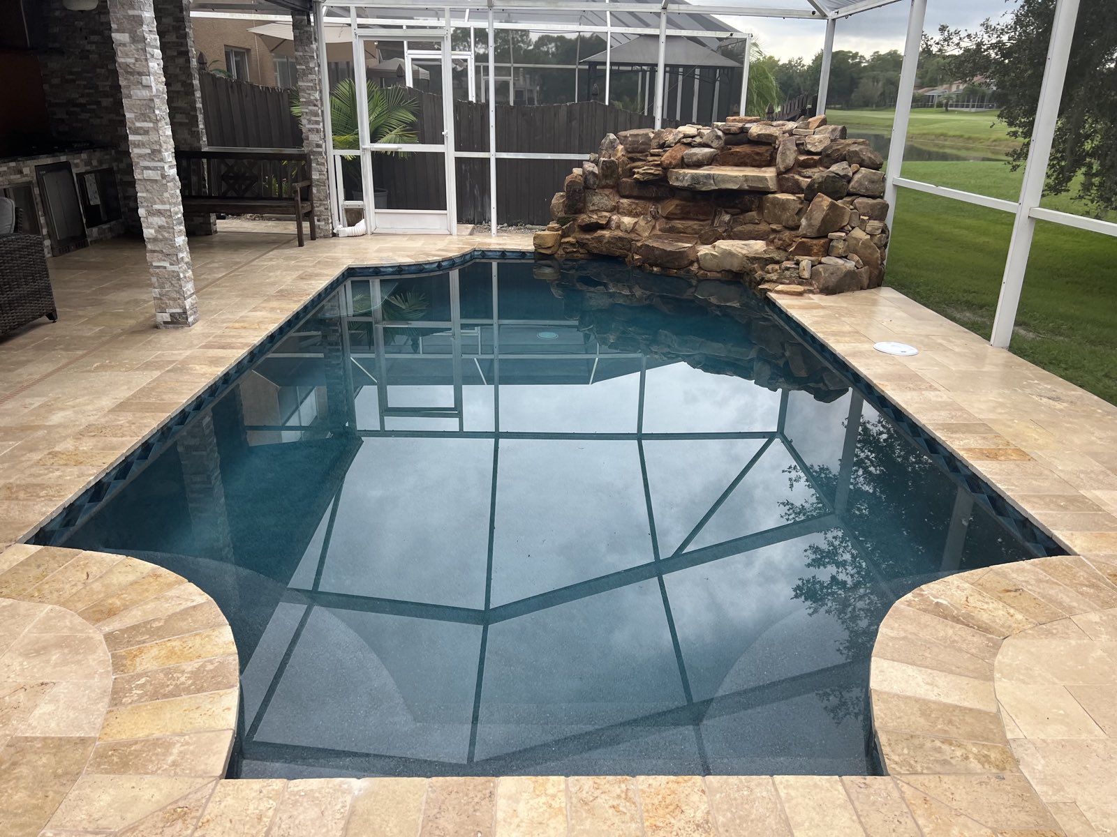 Travertine pool deck under a screen enclosure