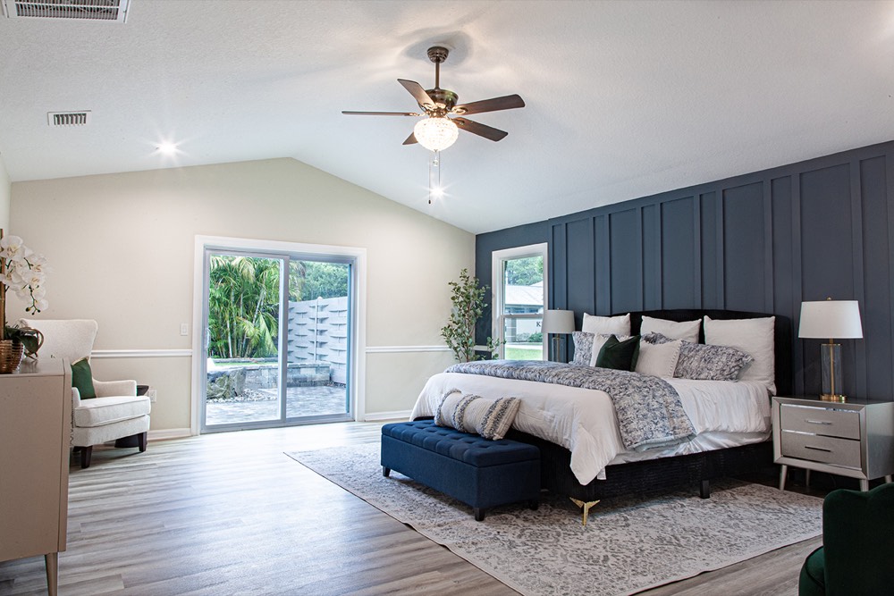 Primary bedroom with a paneled accent wall and vaulted ceiling