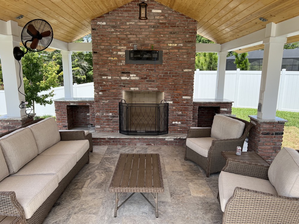 Covered lanai with a brick fireplace and cypress ceiling