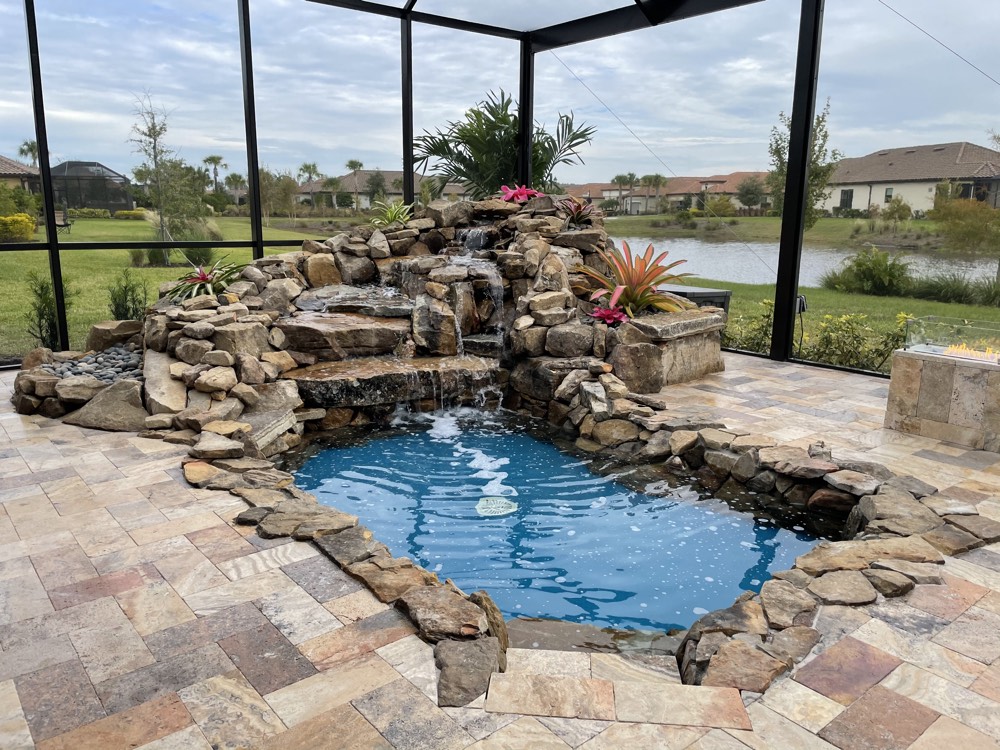Natural rock spa with a waterfall spilling into a screened pool