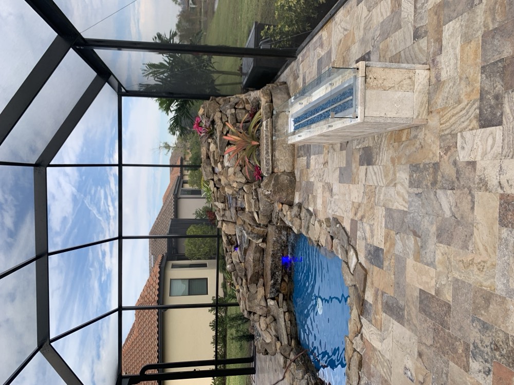 Pool with a natural rock waterfall and linear fire feature